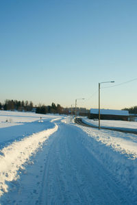 Snow covered land against clear blue sky