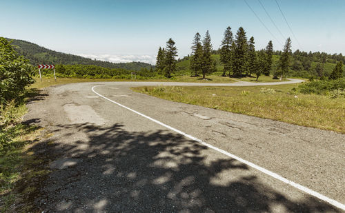 Road by trees against sky