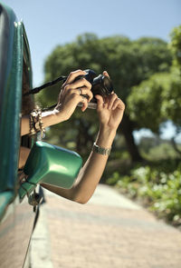 Woman photographing with camera through car window