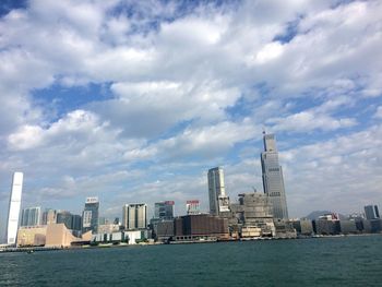 City at waterfront against cloudy sky