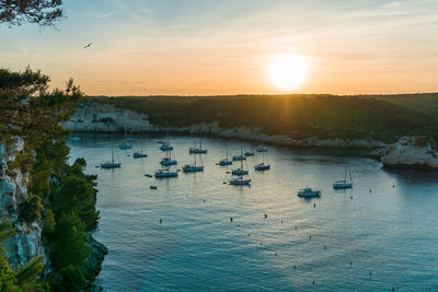 Sailboats in sea against sky during sunset