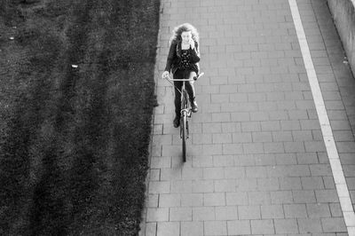 High angle view of woman cycling on footpath