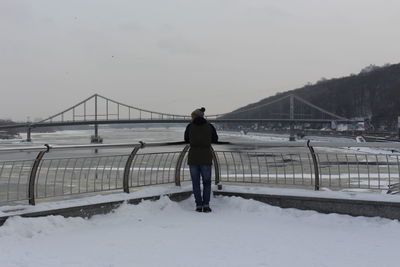 Rear view of man looking at suspension bridge against sky