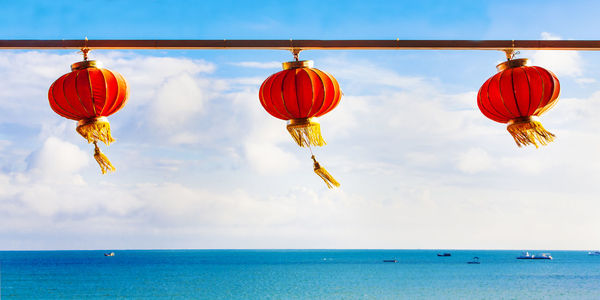 Red chinese paper lanterns against a blue sky and sea