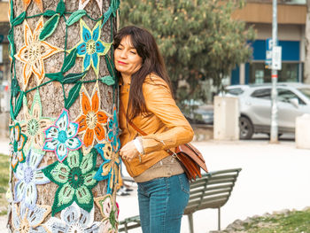 Portrait of young woman hugging a decorated tree