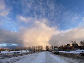 Road by snow covered city against sky