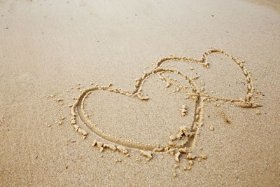Hand drawing a heart shape on sand