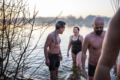 Smiling woman talking with male friend while standing in water