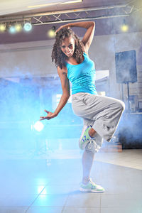 Full length of woman dancing on tiled floor in smoke