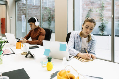 Young woman using mobile phone while sitting on table