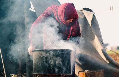 A woman cooks food on wood in a syrian refugee camp.