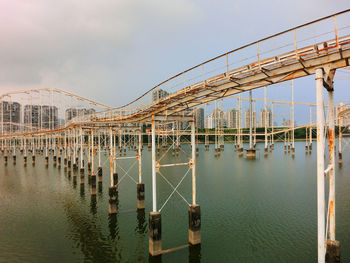 Rollercoaster over river against sky