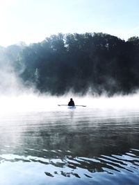Person kayaking on lake during foggy weather