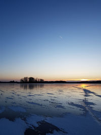 Scenic view of lake against clear sky during sunset