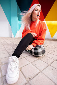 Portrait of young woman sitting on tiled floor