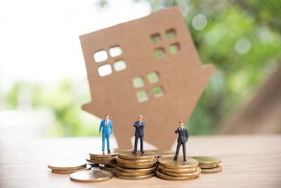 Close-up of figurines with coins and model house on wooden table