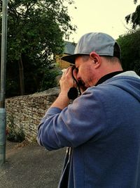 Midsection of man photographing with mobile phone while standing on tree