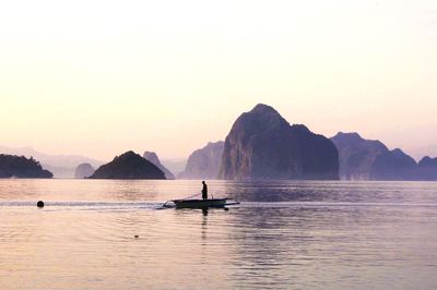 Man sailing boat in sea against clear sky