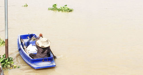 Man sitting in boat against river