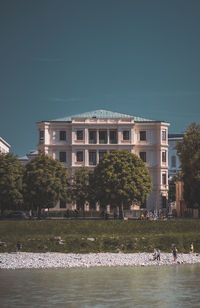 Building by lake in city against sky