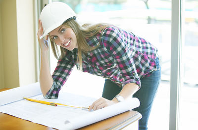 Portrait of smiling architect with blue print on table