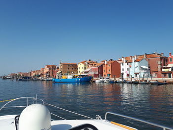 Sea by buildings against clear blue sky