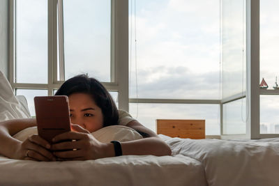 Woman using smart phone on bed at home