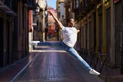 Side view of young woman jumping outdoors