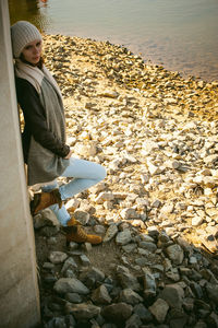 Side view of young woman standing on rocks by river