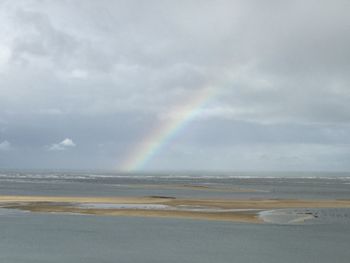 Scenic view of sea against rainbow in sky