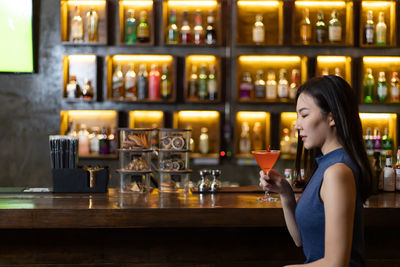 Side view of a young woman drinking glass