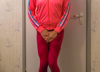Midsection of woman with wet leggings standing against door