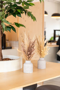 Vases with bouquet of dry flowers on wooden table. minimalist in cafe interior design. cozy design.