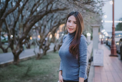 Portrait of smiling young woman standing against trees