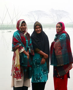 Portrait of smiling friends standing on snow