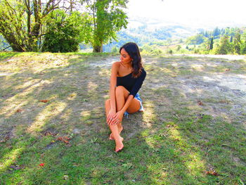 Full length of young woman sitting on land