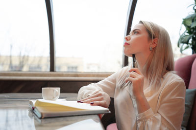 Woman holding coffee cup on table at cafe