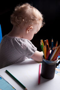 Close-up of boy holding book with pencil on table