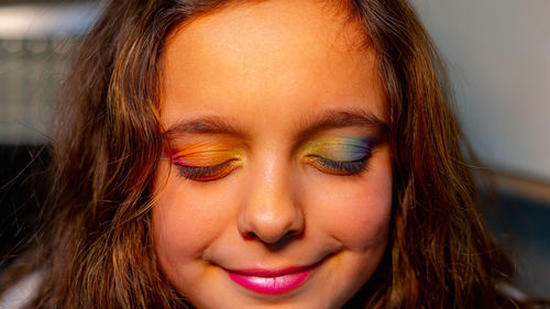 Girl with her eyes closed showing her eyelids painted with the colors of the rainbow