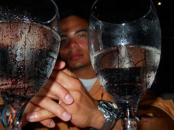 Low angle portrait of young man with wineglasses in bar