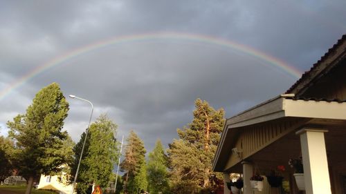 Low angle view of rainbow over trees against sky