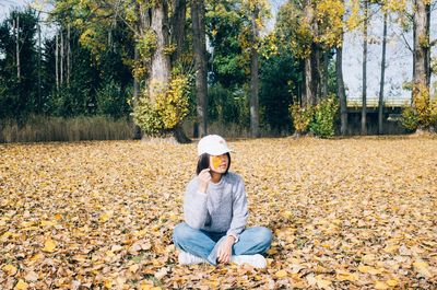 Full length of man sitting on field during autumn
