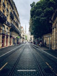 Railroad tracks amidst buildings in city against sky in bordeaux 