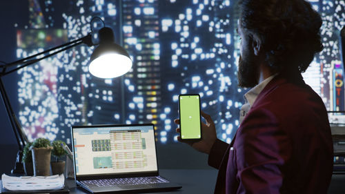 Rear view of man using laptop at office