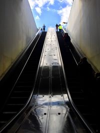 People traveling on escalator against sky