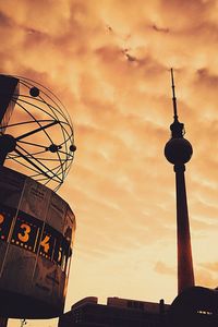 Low angle view of communications tower against cloudy sky