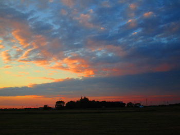 Scenic view of dramatic sky over land during sunset