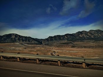 Road by mountains against sky