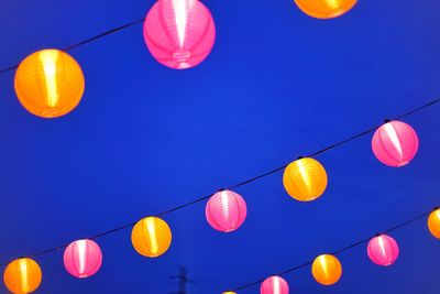 Low angle view of lanterns hanging against clear blue sky