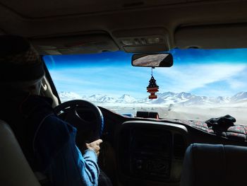 Rear view of man driving car against sky